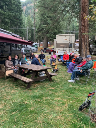 Group gathered in campground with mountains in background.